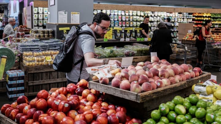 Comprador revisando precios de frutas en supermercado en EE. UU. ante aumento de la inflación